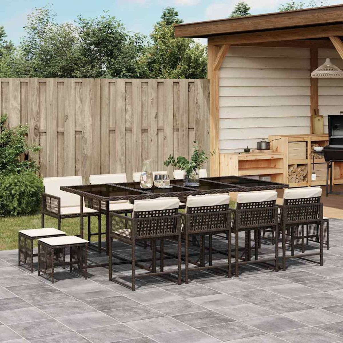 Set da pranzo all'aperto con cuscini bianchi. Patio con struttura in legno e piante.