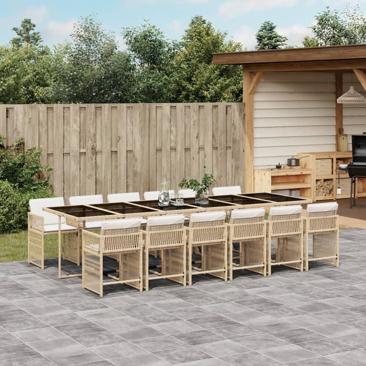 Ampio set da pranzo all'aperto. Tavolo, 12 sedie. Materiale intrecciato. Ambiente patio con recinzione in legno.