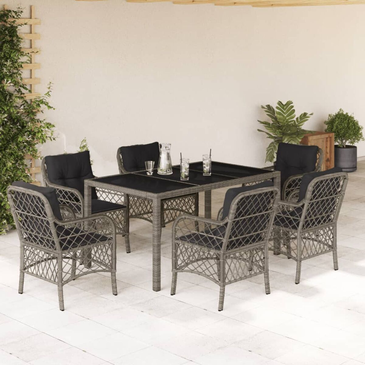 Essgruppe im Freien mit Tisch und Stühlen. Der Tisch hat eine dunkle Oberfläche. Stühle haben schwarze Kissen.