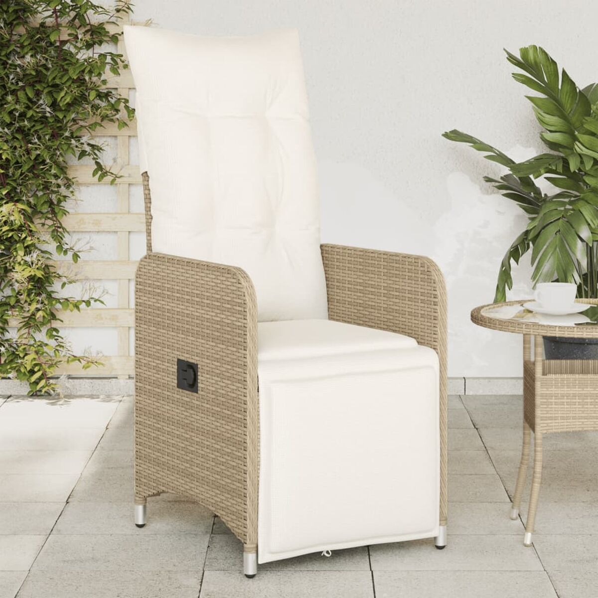 Beiger Rattan-Liegesessel mit weißem Kissen. Ein kleiner Beistelltisch und eine Pflanze sind in der Nähe.