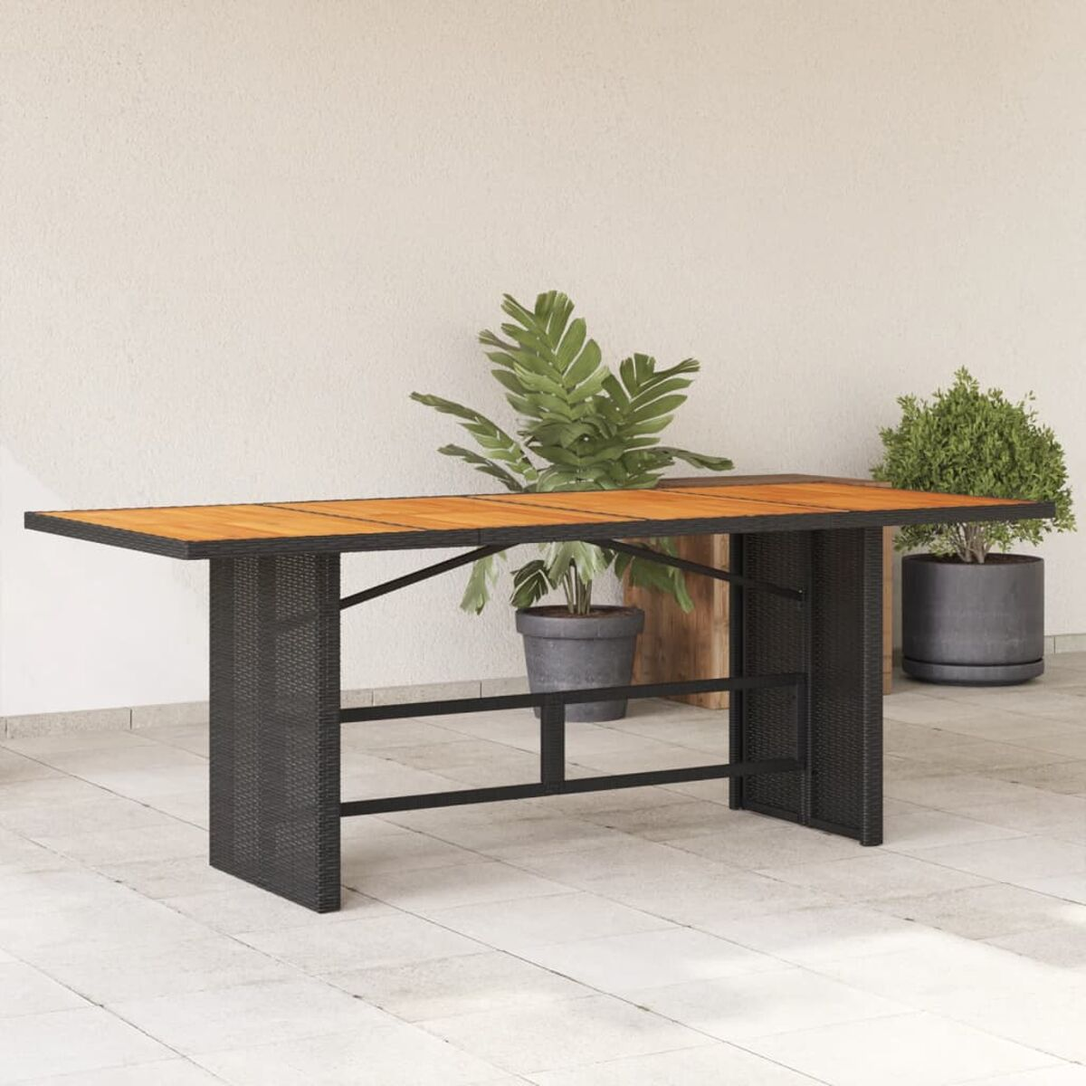 Tavolo da bar all'aperto con lati neri intrecciati, piano in legno e piante.