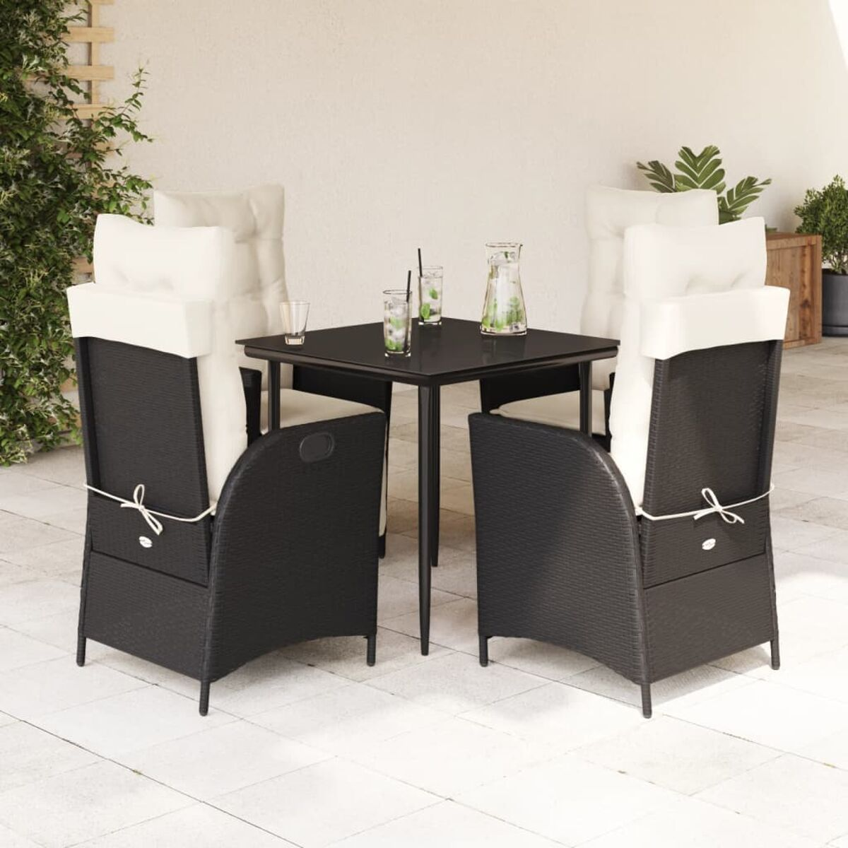 Ein kleines Ess-Set für den Außenbereich mit quadratischem Tisch, vier Stühlen und Gläsern. Auf einer Terrasse.