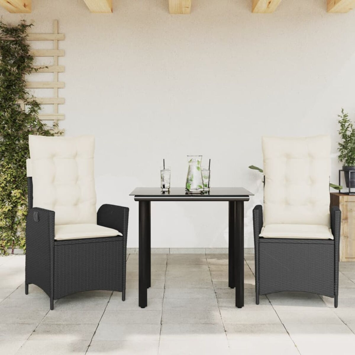 Zwei schwarze Korbstühle, ein quadratischer Tisch und Gläser oben drauf. Der Hintergrund ist weiß.