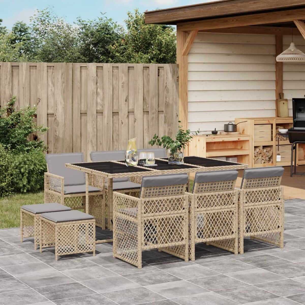 Set da patio con tavolo e sedie. Cuscini grigi. Sfondo recinzione in legno. Ambiente esterno.