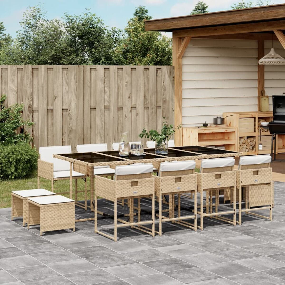 Essgruppe im Freien mit Tisch und Stühlen auf einer Terrasse. Pflanzen im Hintergrund.