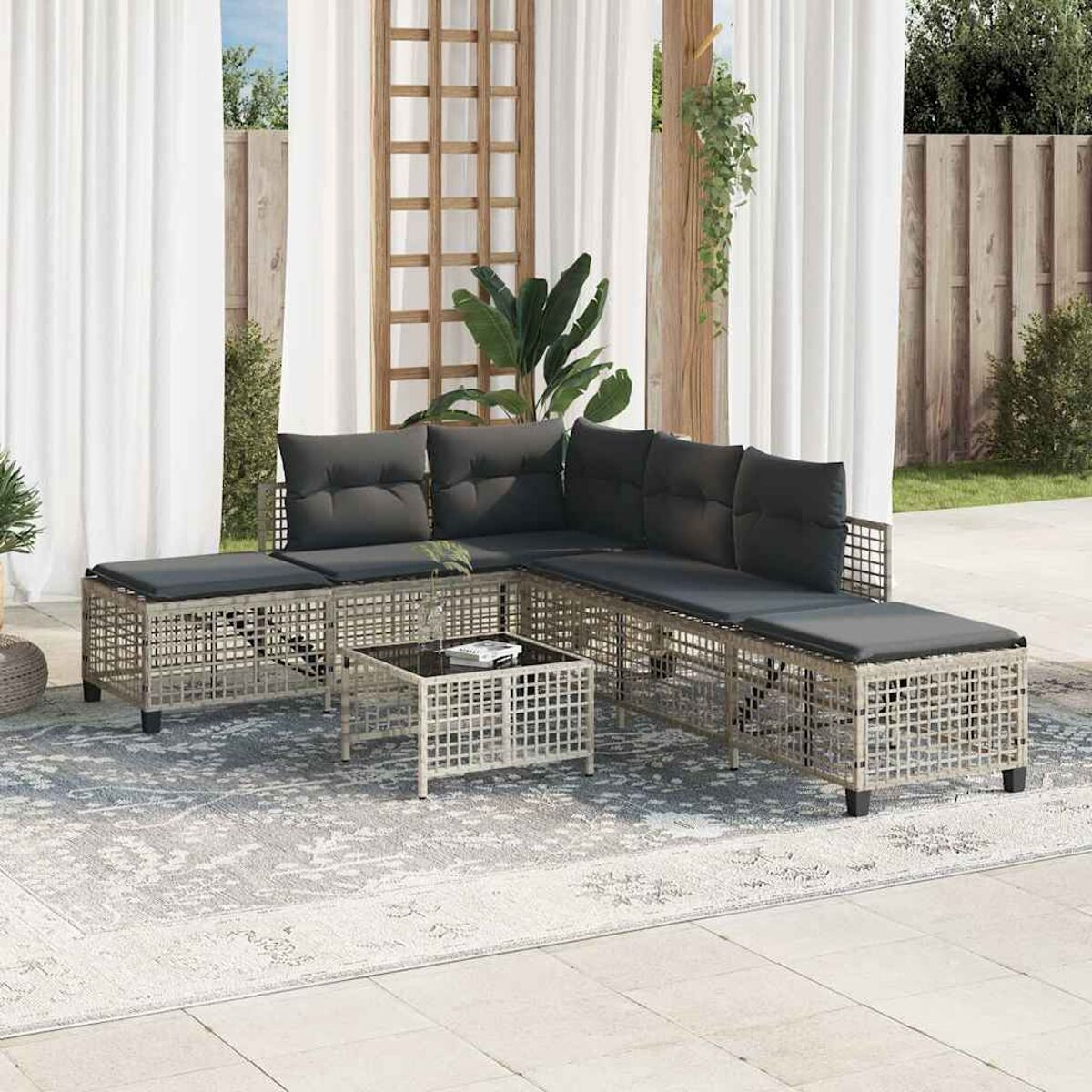 L-förmiges Outdoor-Sofagarnitur mit kleinem Tisch auf gemustertem Teppich im Garten.