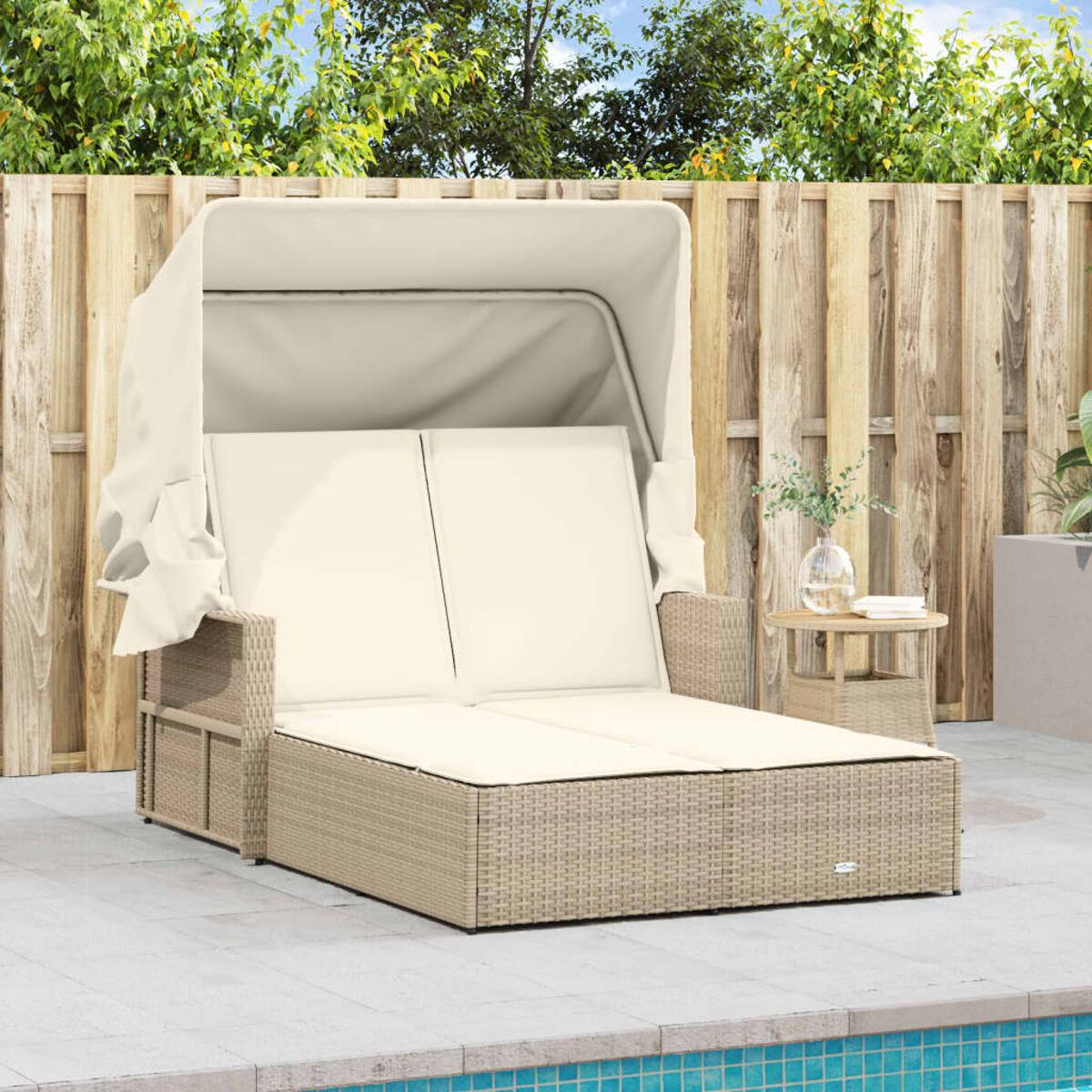 Outdoor-Korbliege mit Baldachin. Beiges Gestell und Kissen. Pool und Holzzaun sichtbar.