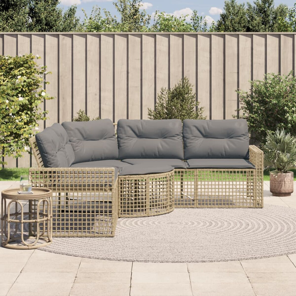 Set divano angolare in vimini beige con cuscini grigi su un tappeto circolare.