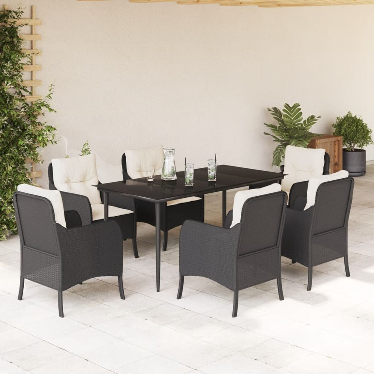 Ein schwarzes Tisch- und Stuhlset auf einer Terrasse. Auf dem Tisch stehen Getränke und eine Kanne. Die Stühle haben Kissen.