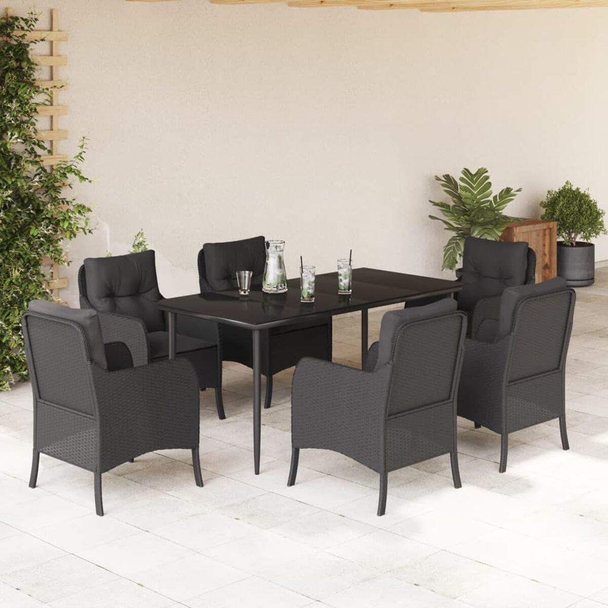 Essgruppe für den Außenbereich. Schwarze Korbstühle und ein schwarzer Tisch. Weißer Hintergrund und Wand.