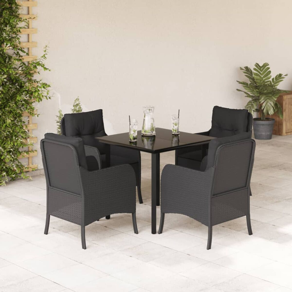 Outdoor-Tischset mit Stühlen. Schwarzes Korbgeflecht mit schwarzen Kissen, Getränke auf dem Tisch, Terrasse.