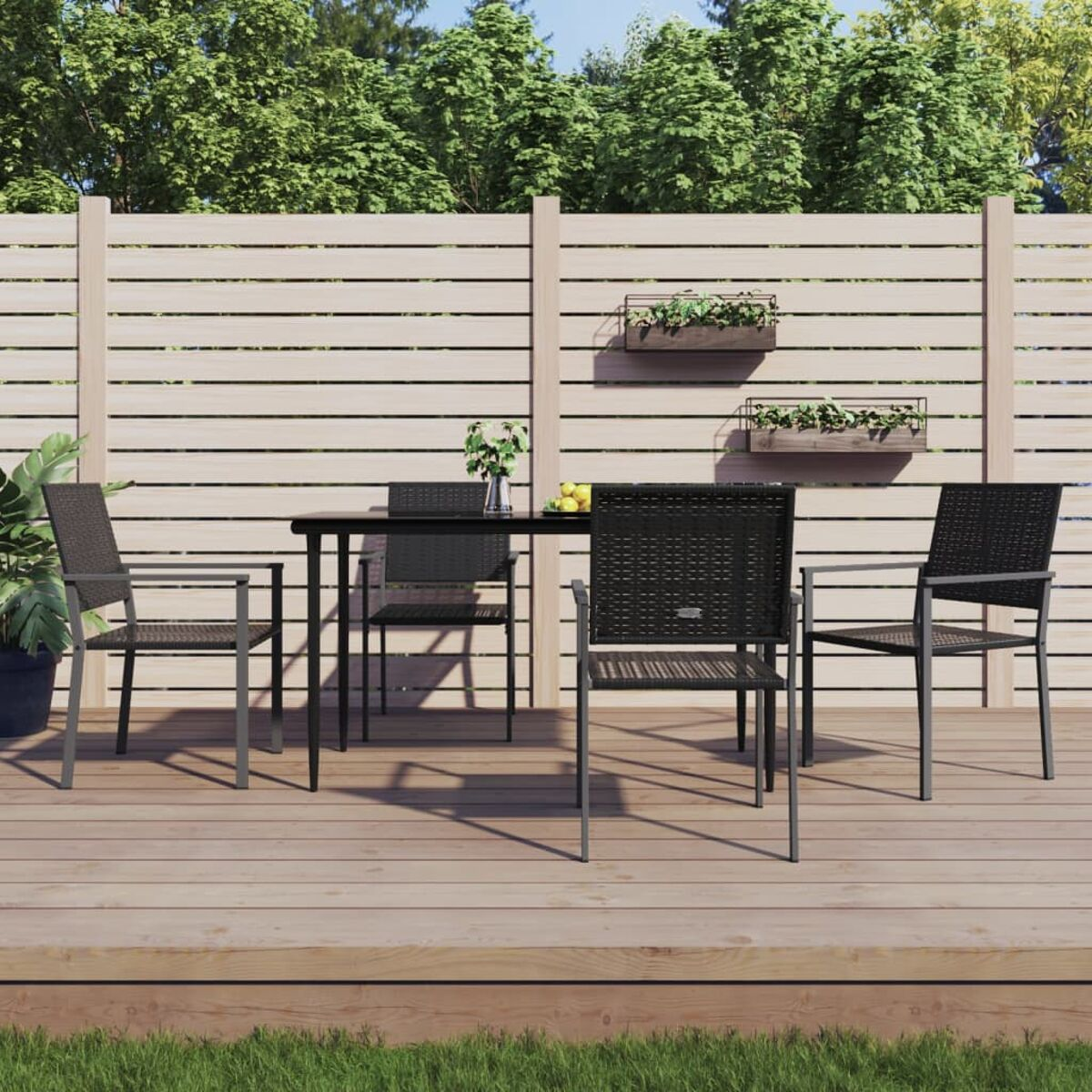 Essgruppe im Freien. Ein schwarzer Tisch mit vier Stühlen auf einer Holzterrasse mit Zaun.