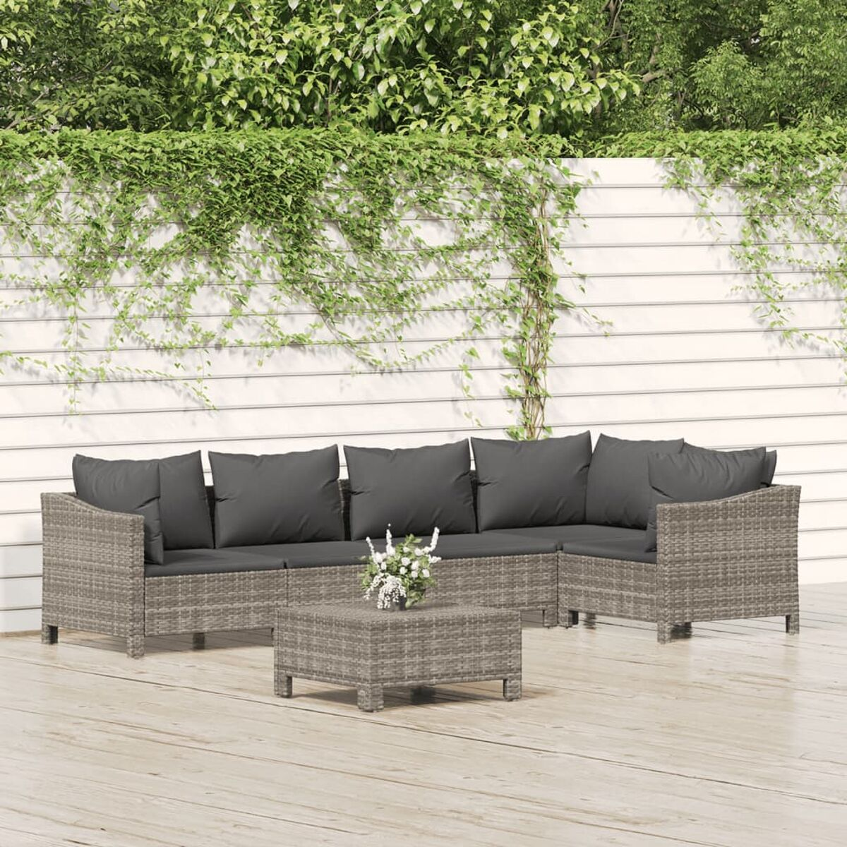 Graues Sitzensemble für den Außenbereich mit Sofa, zwei Sesseln und einem Couchtisch vor Grün.
