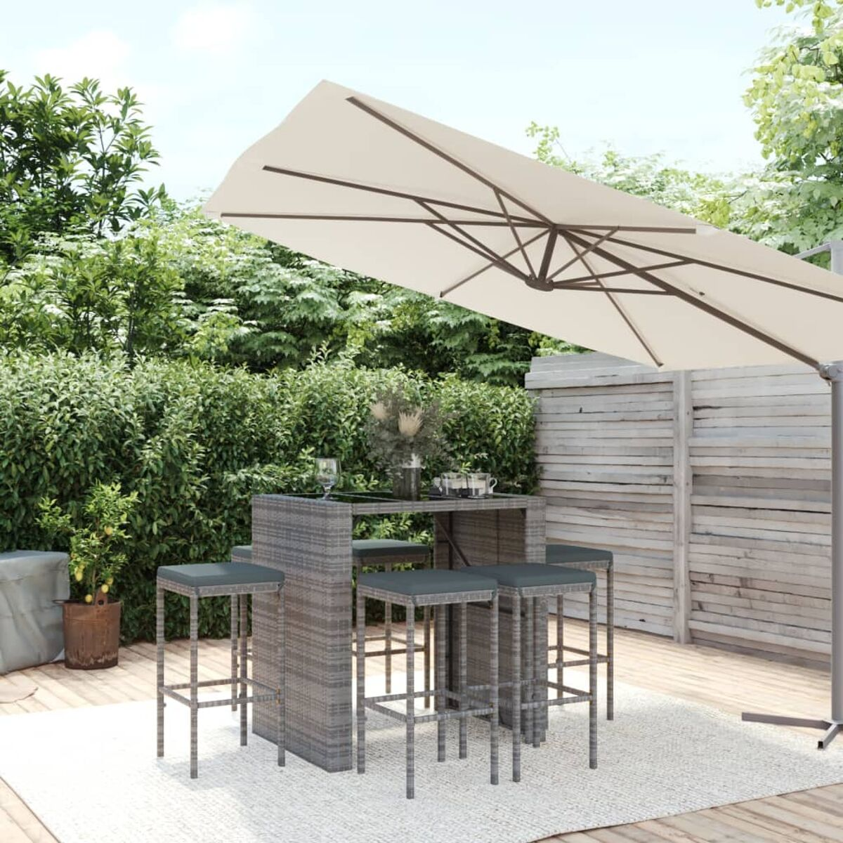 Korbmöbel-Bar-Set mit Schirm, Hockern und Tisch auf einem Deck.