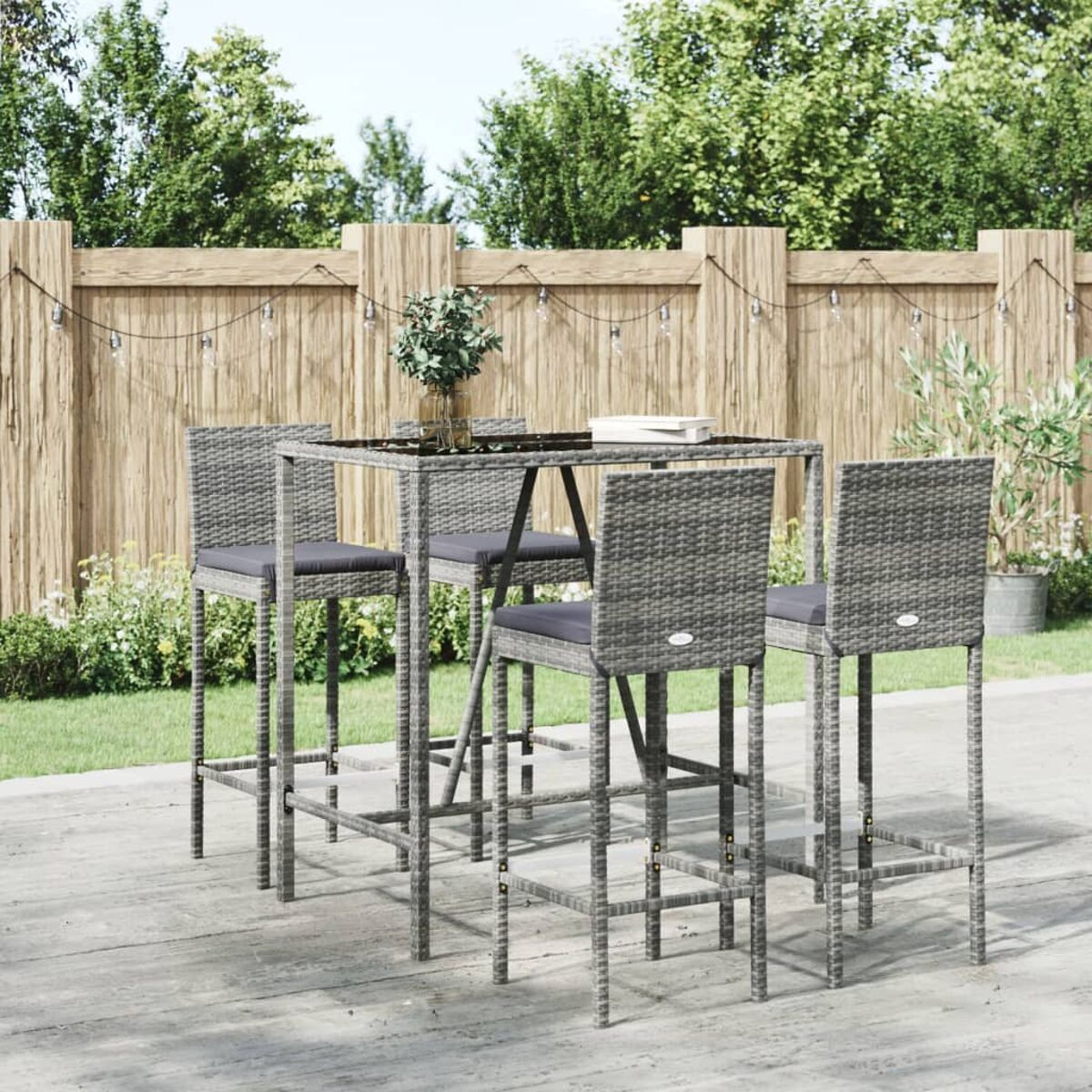 Gartenbar-Set mit Tisch und Hockern. Tisch und Hocker haben graue Kissen. Holzterrasse im Hintergrund.