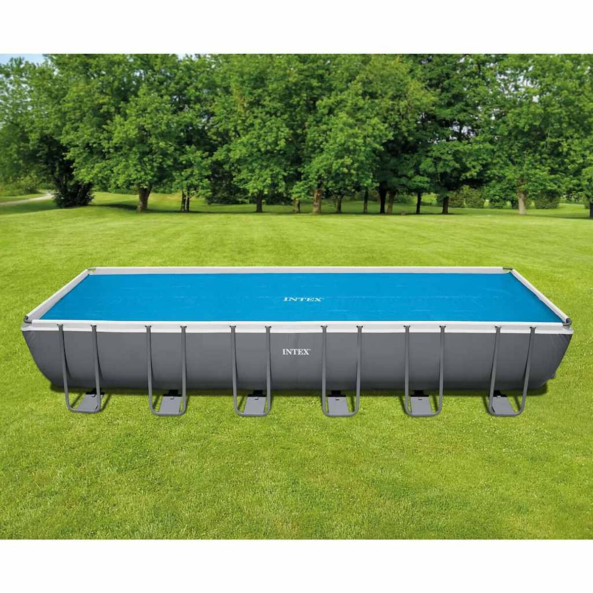 Ein rechteckiger oberirdischer Swimmingpool mit blauer Abdeckung, umgeben von grünem Gras.