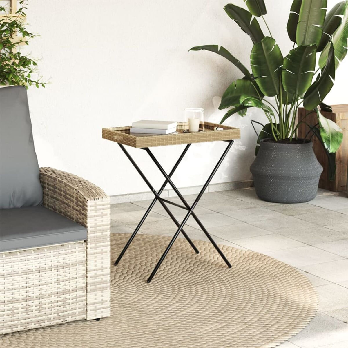 Ein Beistelltisch aus Korbgeflecht mit Tablett, Büchern und einer Kerze auf einer Terrasse.