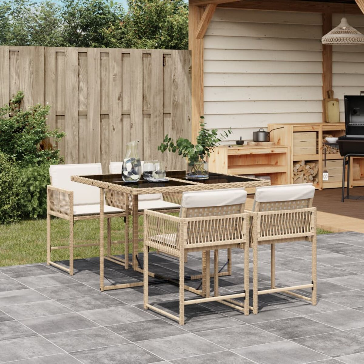 Set da pranzo all'aperto: tavolo, quattro sedie su un patio con struttura in legno sullo sfondo.