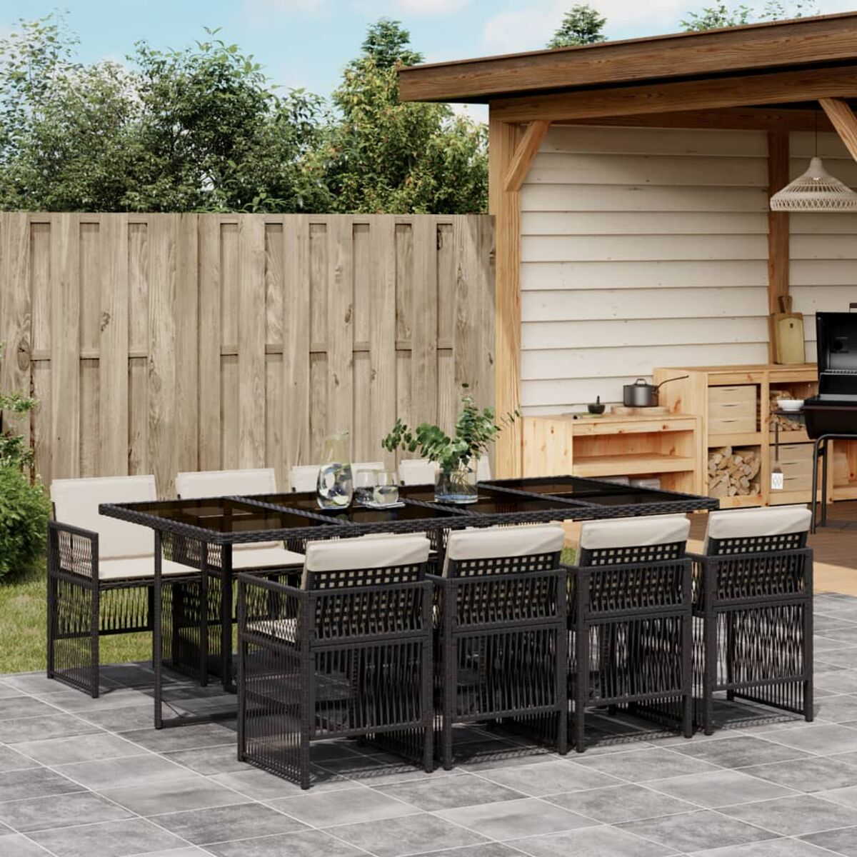 Set da patio con tavolo, sedie e bevande. Vimini nero con cuscini beige, su un patio.