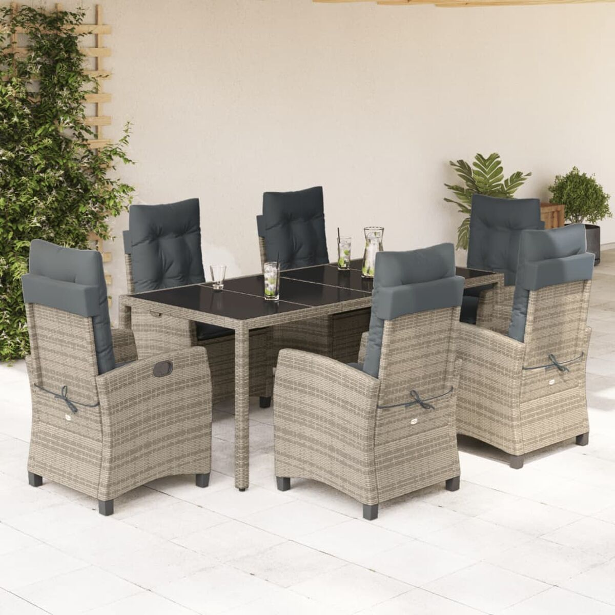 Essgruppe im Freien mit Tisch und sechs grau gepolsterten Stühlen auf einer gefliesten Terrasse. Pflanzen im Hintergrund.