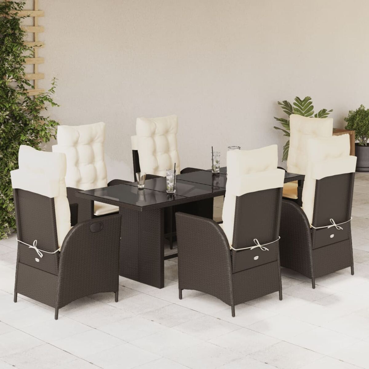 Essgruppe im Freien mit dunkelbraunen Stühlen und einem Tisch. Beige Kissen und Pflanzen im Hintergrund.