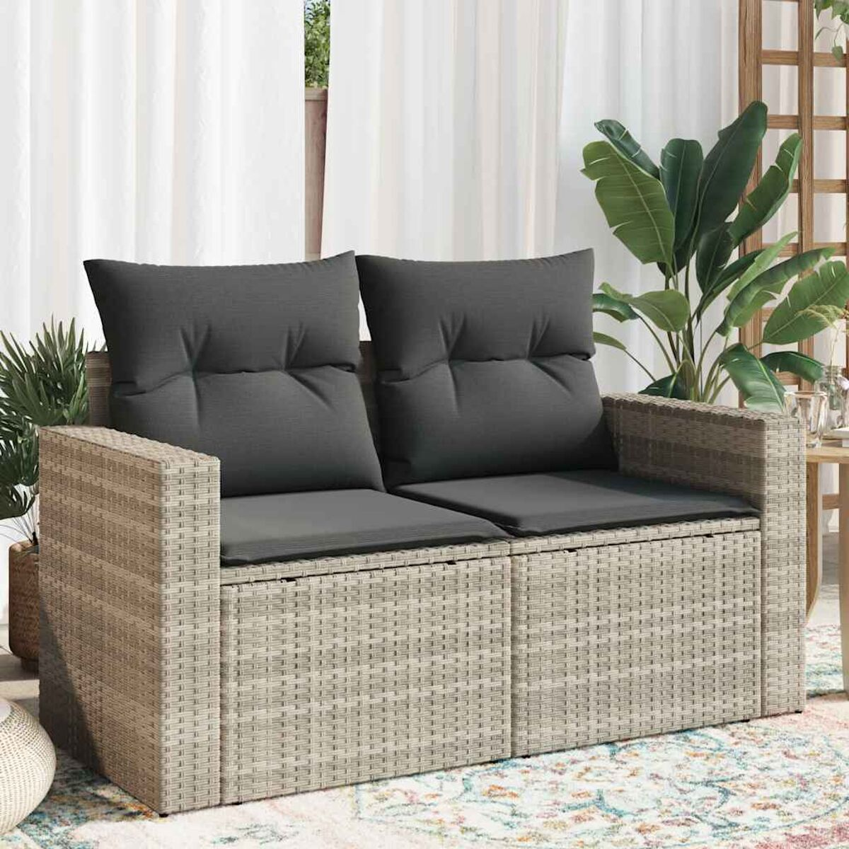 Ein Zweisitzer-Sofa aus Korbgeflecht mit dunkelgrauen Kissen.