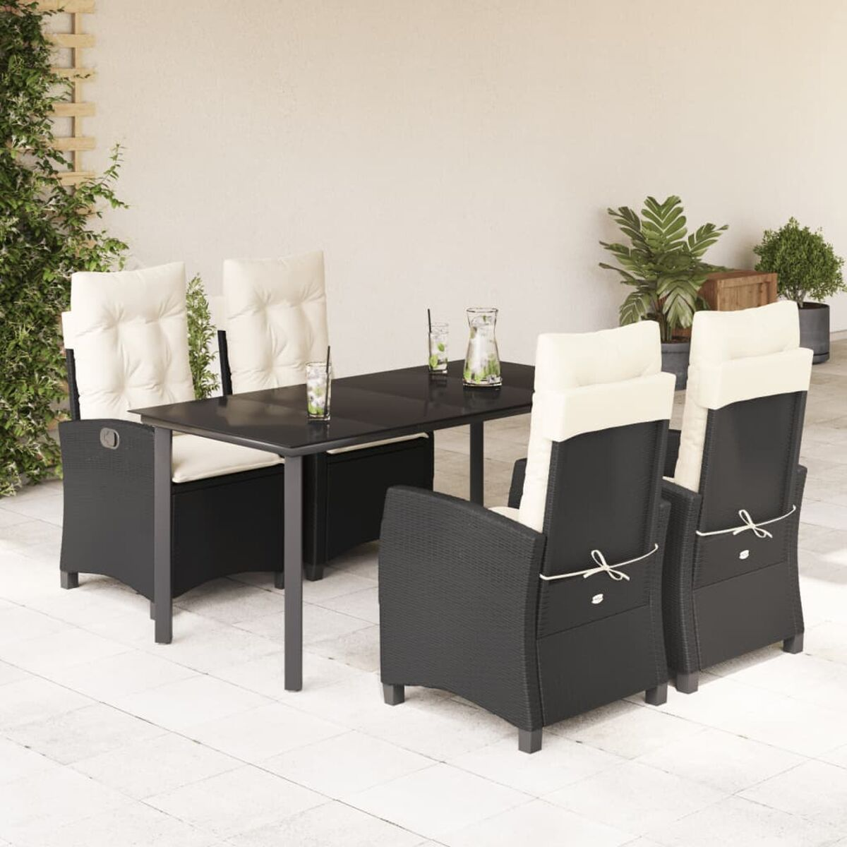 Ein Terrassenset mit schwarzen Korbstühlen und Tisch. Die Stühle haben weiße Kissen. Die Umgebung ist im Freien.