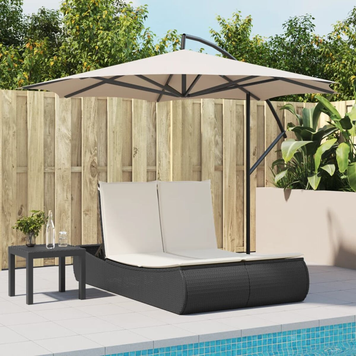 Zona relax all'aperto. Lettino doppio in vimini nero con ombrellone e tavolino.
