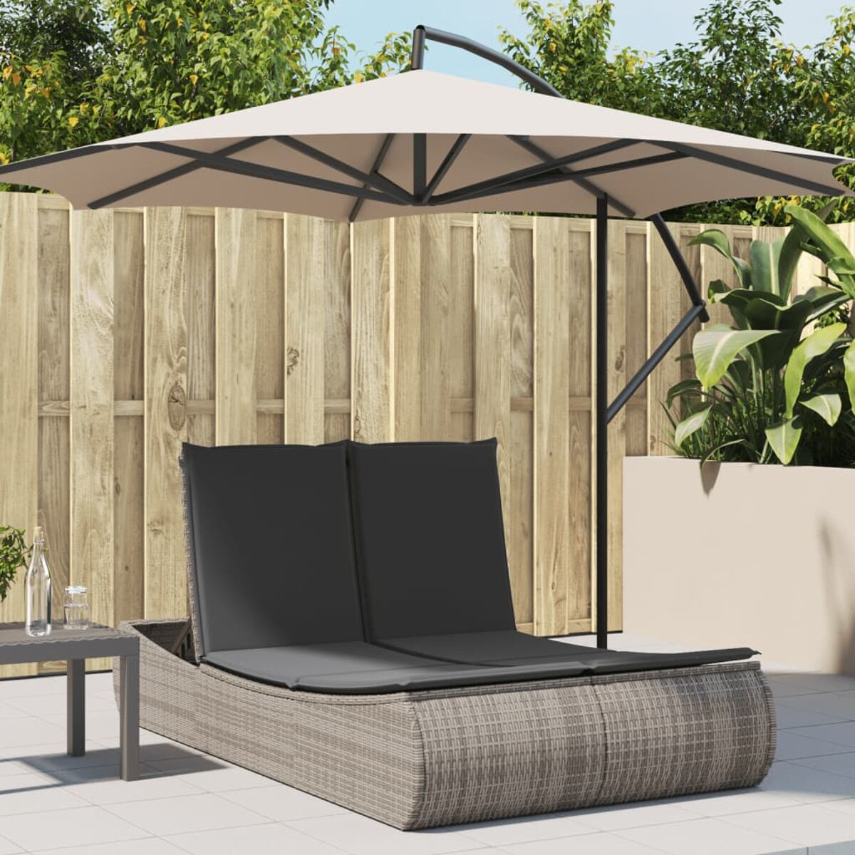 Outdoor-Daybed mit schwarzen Kissen und einem beigen Schirm, Holzzaun im Hintergrund.