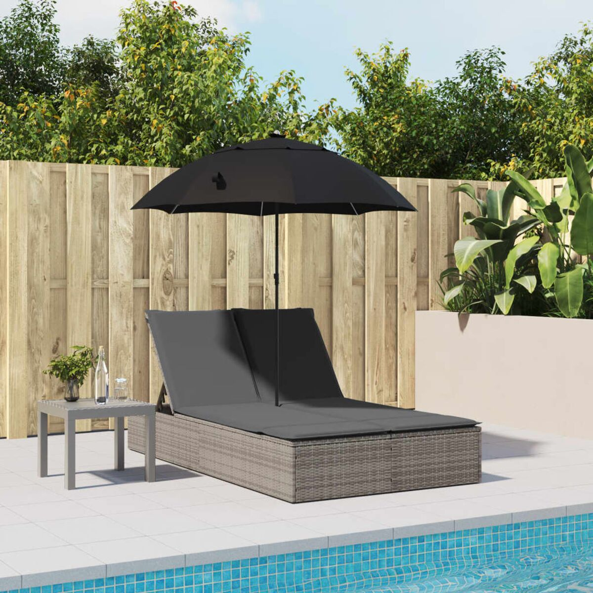 Lettino doppio con ombrellone nero. Tavolo con acqua e piante. Piscina sullo sfondo.