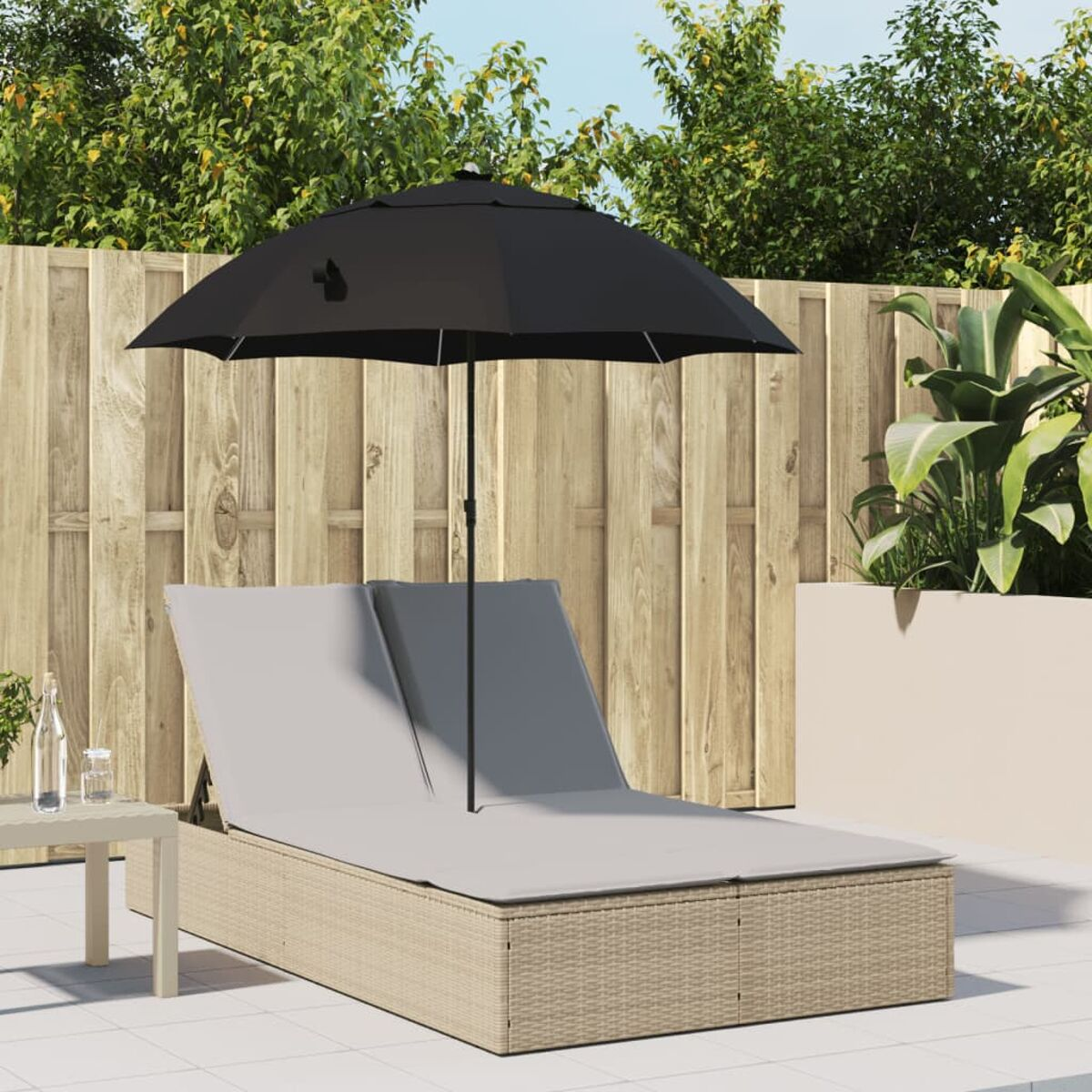 Lettini prendisole all'aperto. Rattan con cuscini grigi. Ombrellone nero. Recinzione in legno.
