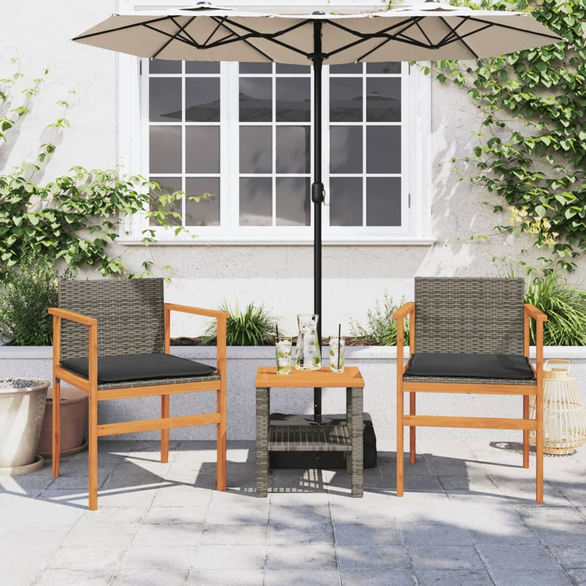 Zwei Rattanstühle mit grauen Kissen und kleinem Tisch mit Getränken unter einem großen beigen Schirm.