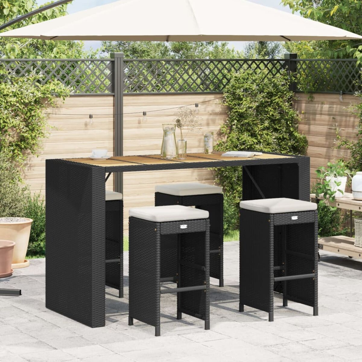 Set da pranzo all'aperto con tavolo nero, quattro sgabelli e ombrellone beige.