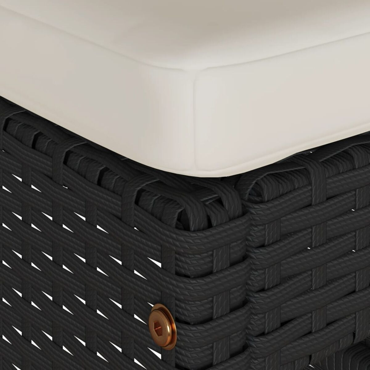 Primo piano di un angolo in rattan nero che mostra un cuscino color crema.