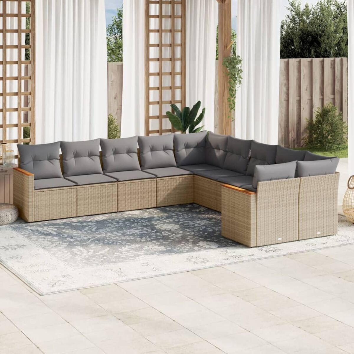 L-förmiges beiges Korbmöbelsofa mit grauen Kissen auf einer Terrasse, einem Teppich und Vorhängen im Hintergrund.