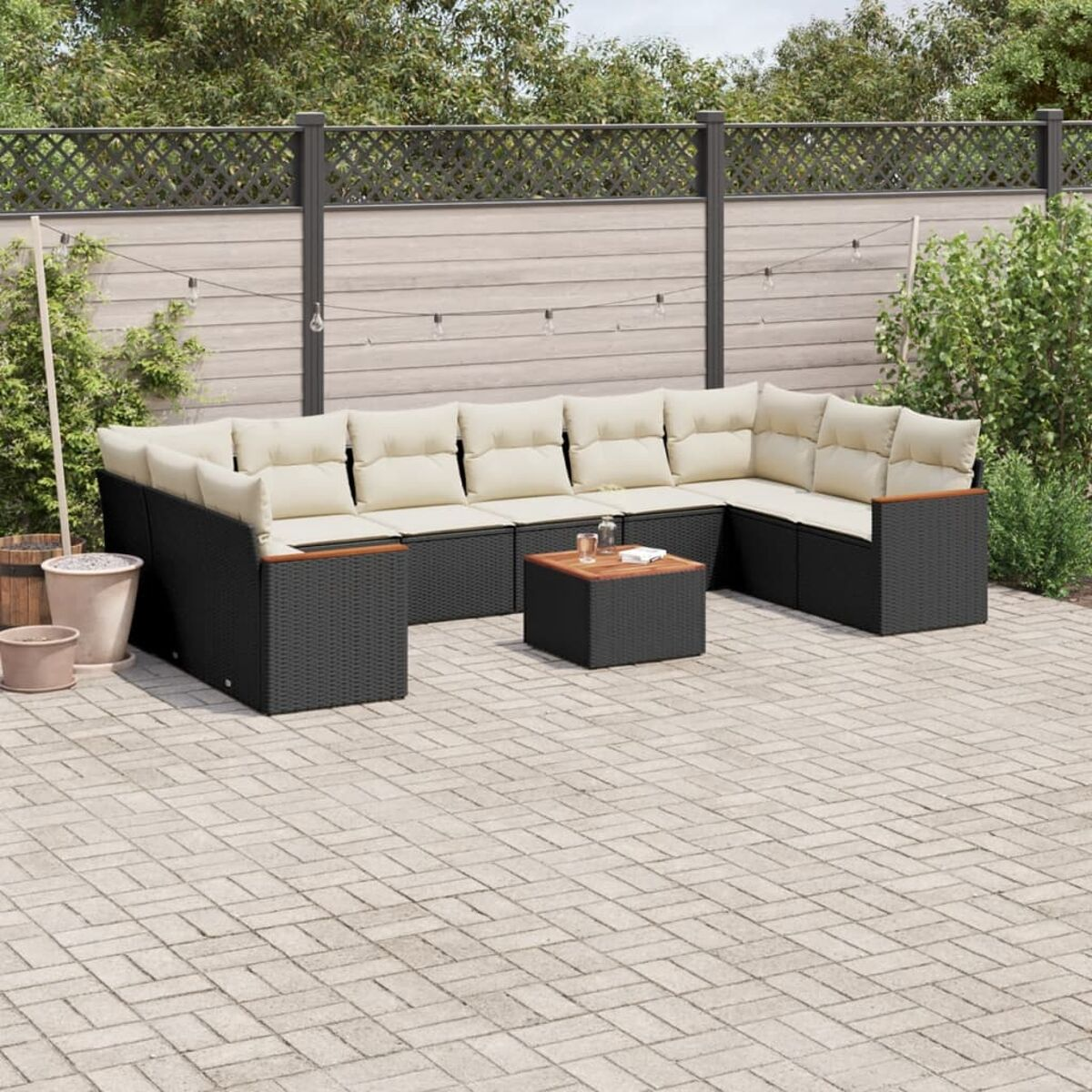 Set patio esterno con mobili neri intrecciati, cuscini crema e tavolo.