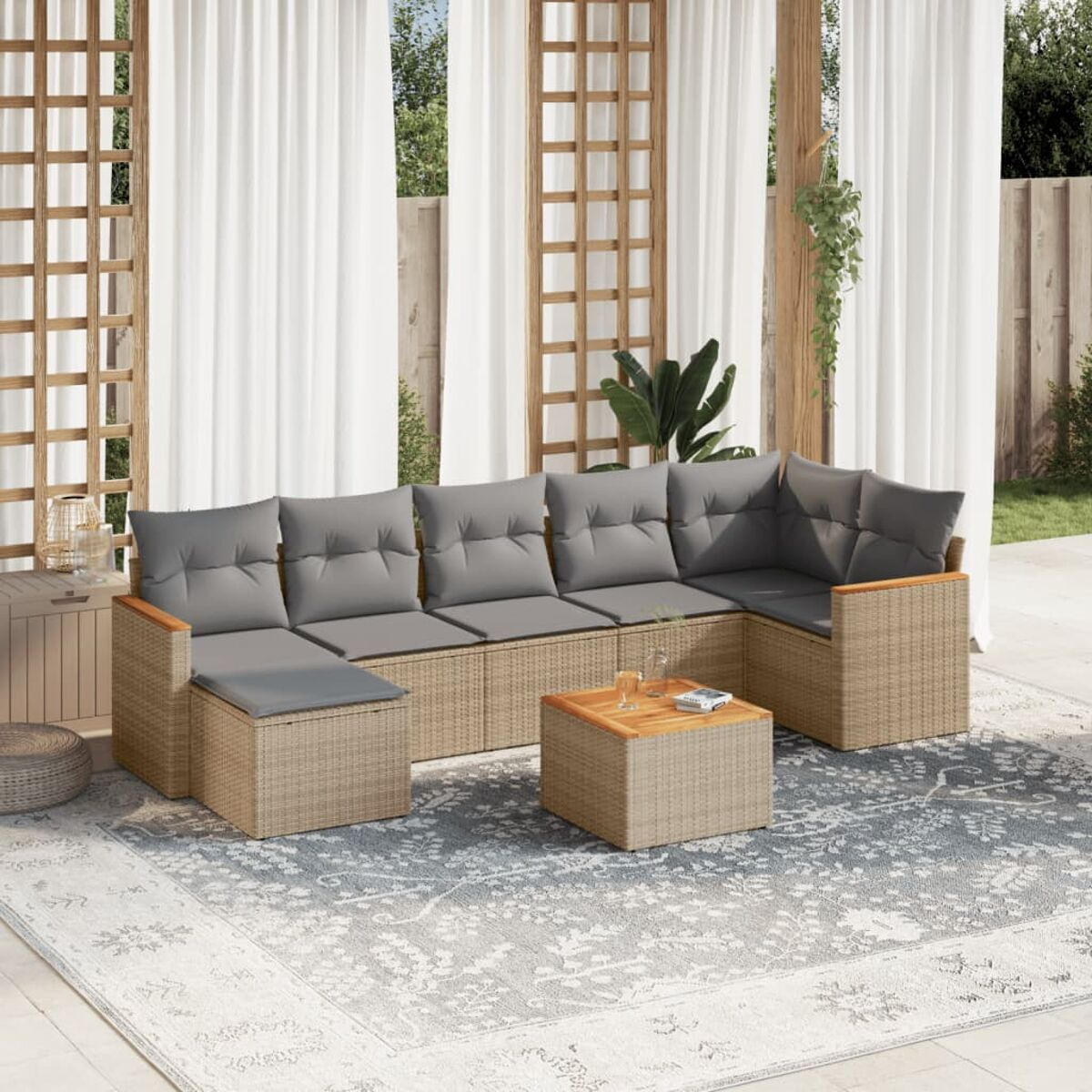 Beiges Rattan-Terrassenmöbel-Set. Graue Kissen. Weiße Vorhänge im Hintergrund.
