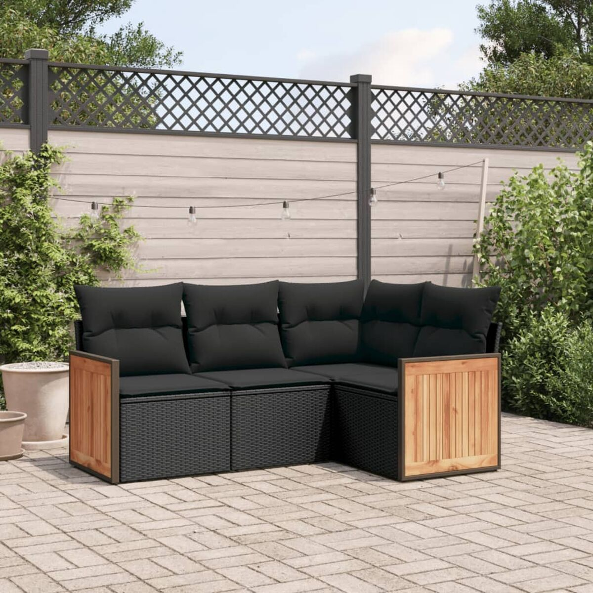 Schwarzes Rattan-Ecksofa mit Holzakzenten und schwarzen Kissen. Auf einer Terrasse.