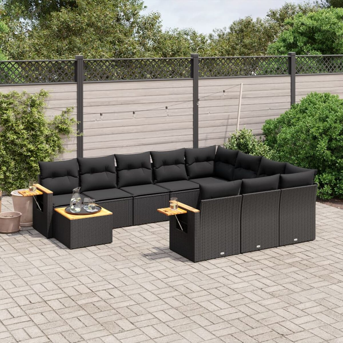 Outdoor-Sitzgruppe mit schwarzen Kissen. Enthält ein Ecksofa, zwei Beistelltische und eine Backstein-Terrasse.