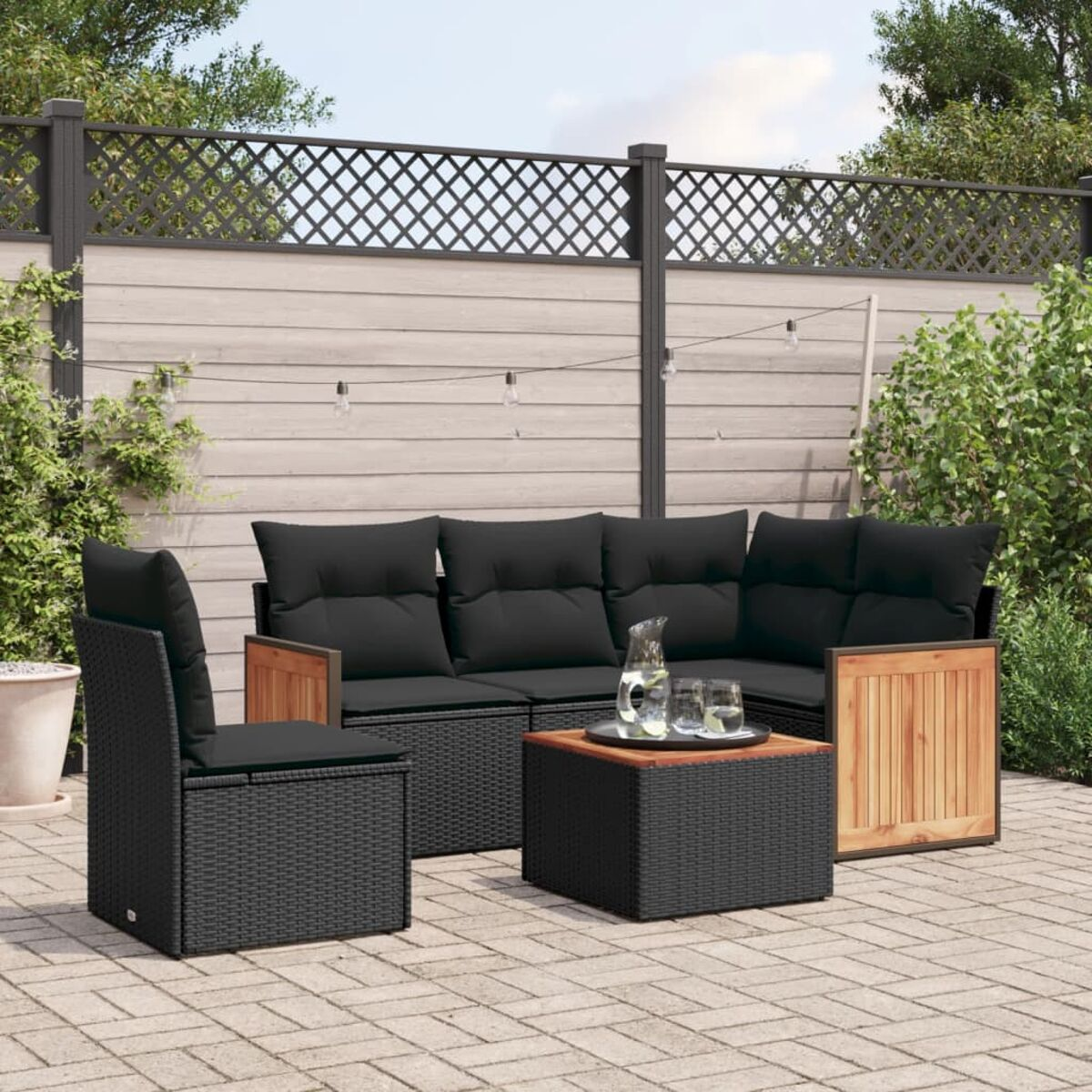 Schwarzes Ecksofa aus Korbgeflecht für den Außenbereich mit schwarzen Kissen, auf der Terrasse.