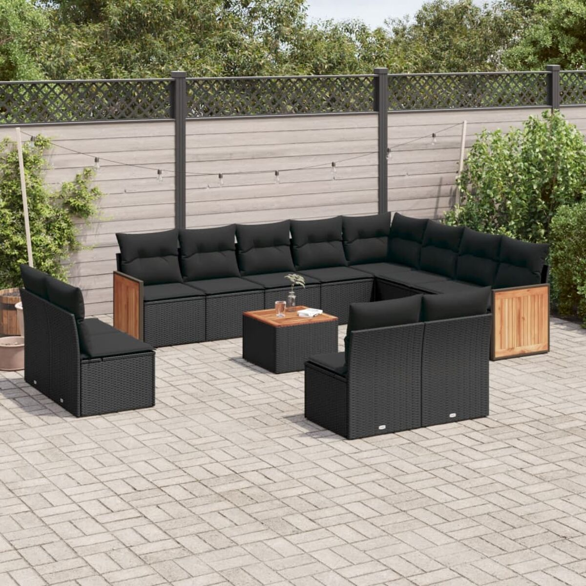 Ein schwarzes Outdoor-Sofa mit Kissen, Tischen und einer Backstein-Terrasse.