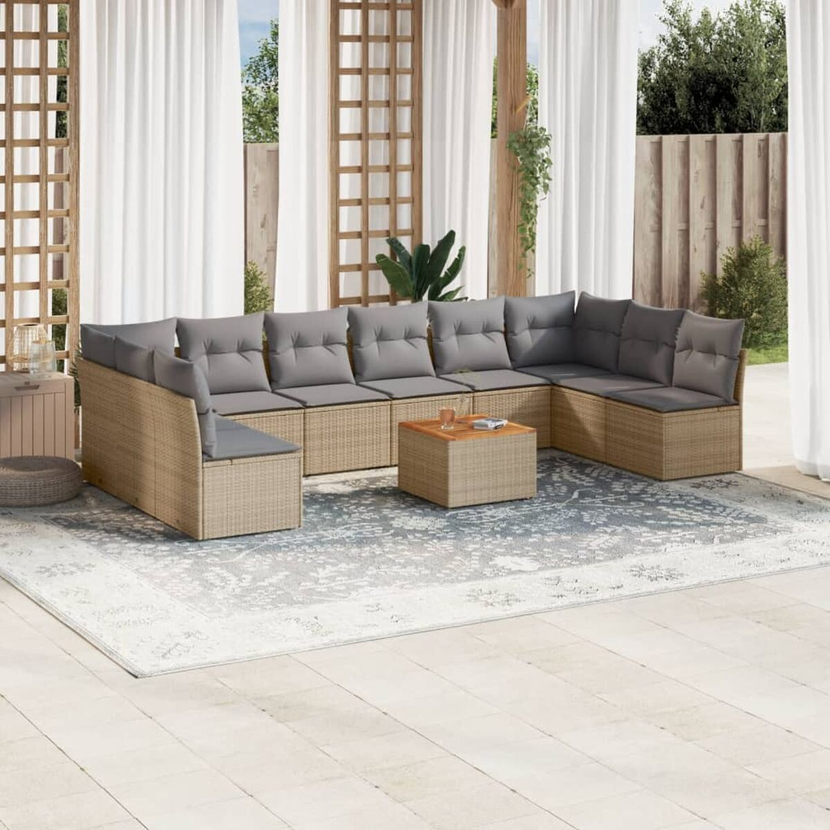 Beiges Outdoor-Möbelset aus Korbgeflecht. Enthält ein Sofa, Stühle und einen Tisch auf einer Terrasse. Vorhänge im Hintergrund.