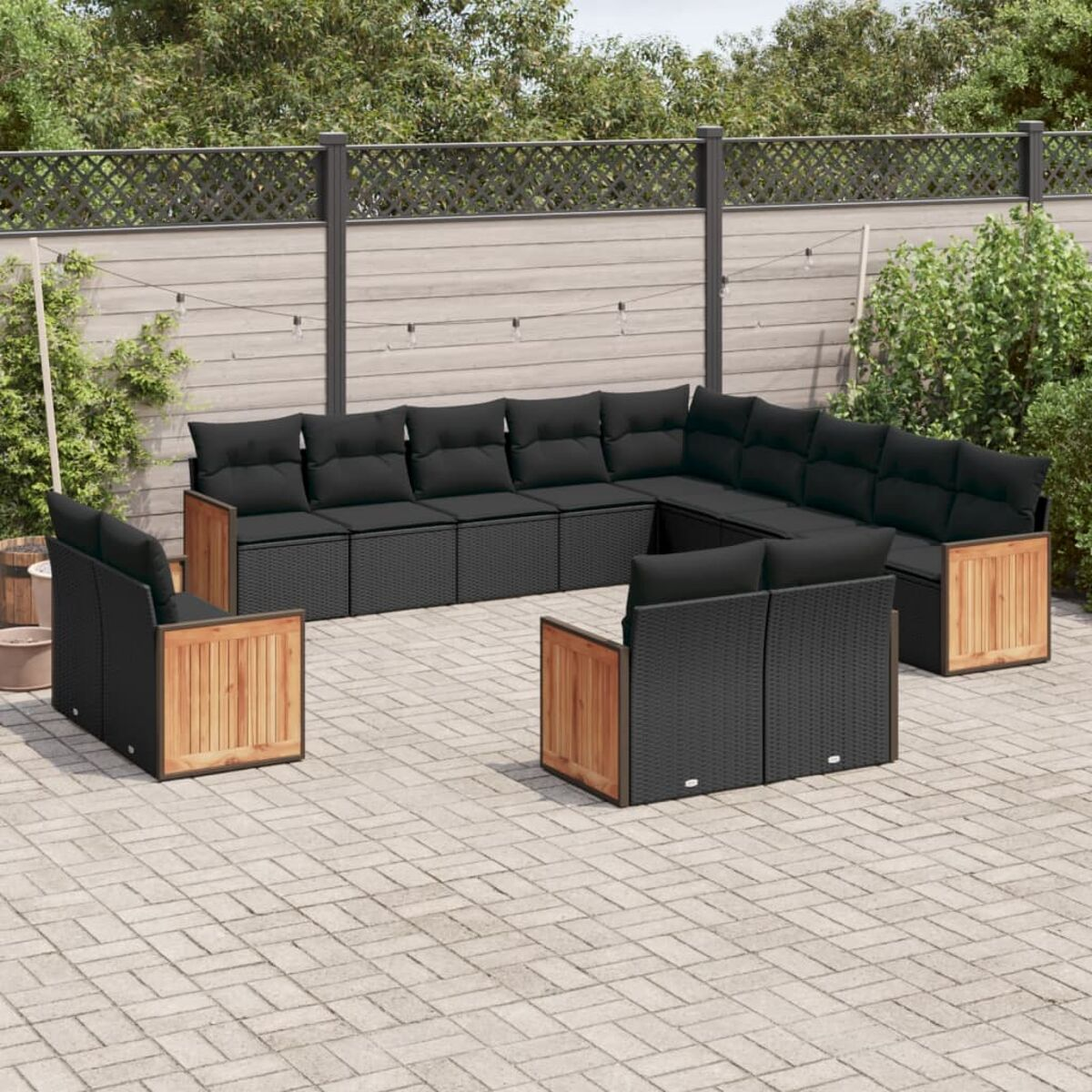 Gartenmöbelset mit schwarzen Kissen, Holzakzenten auf einer Ziegelterrasse.