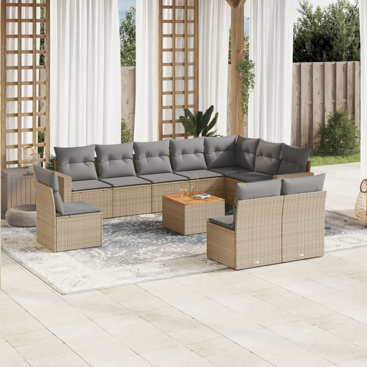 Terrassen-Set: L-förmiges Rattan-Sofa mit grauen Kissen, Holztisch, auf Teppich mit Vorhängen.