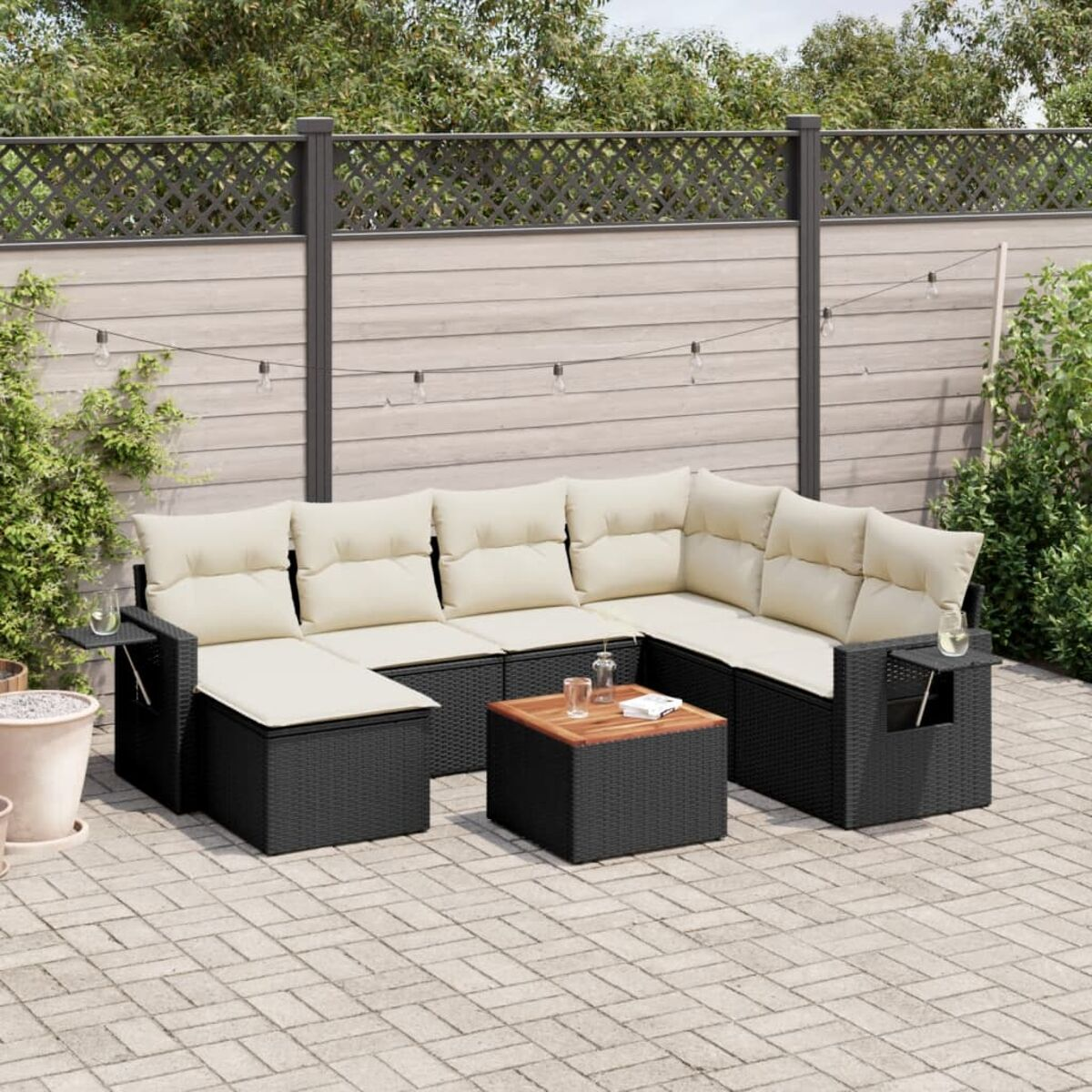 Schwarzes Ecksofa mit beigen Kissen. Ein kleiner Holztisch steht davor. Kleine Beistelltische sind an den Seiten.