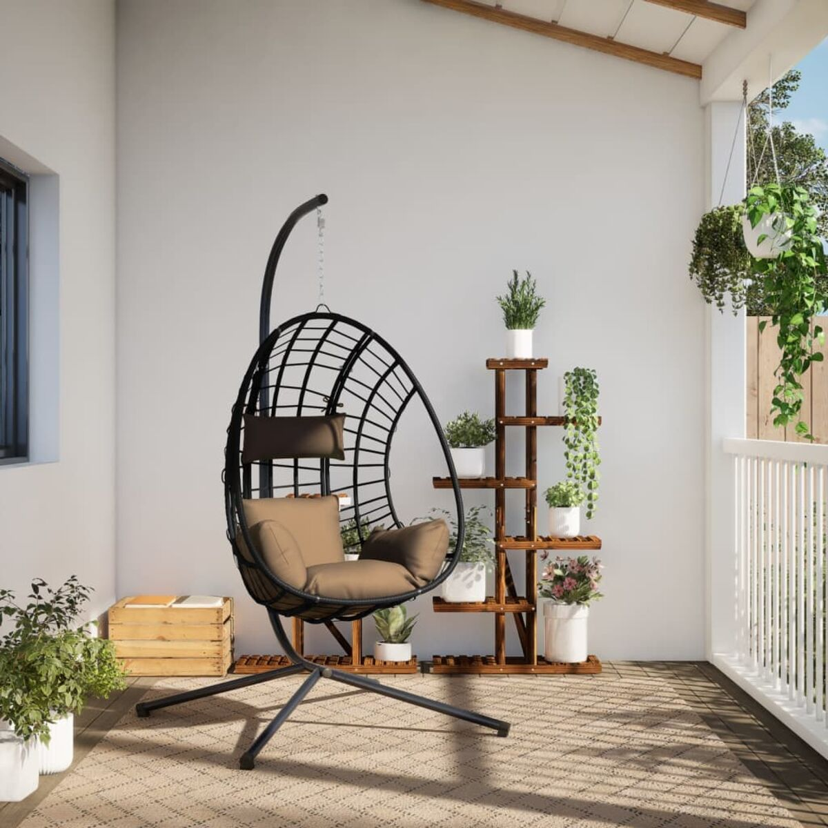 Sedia sospesa a uovo nera, cuscino beige, con piante e portapiante su una terrazza in legno.