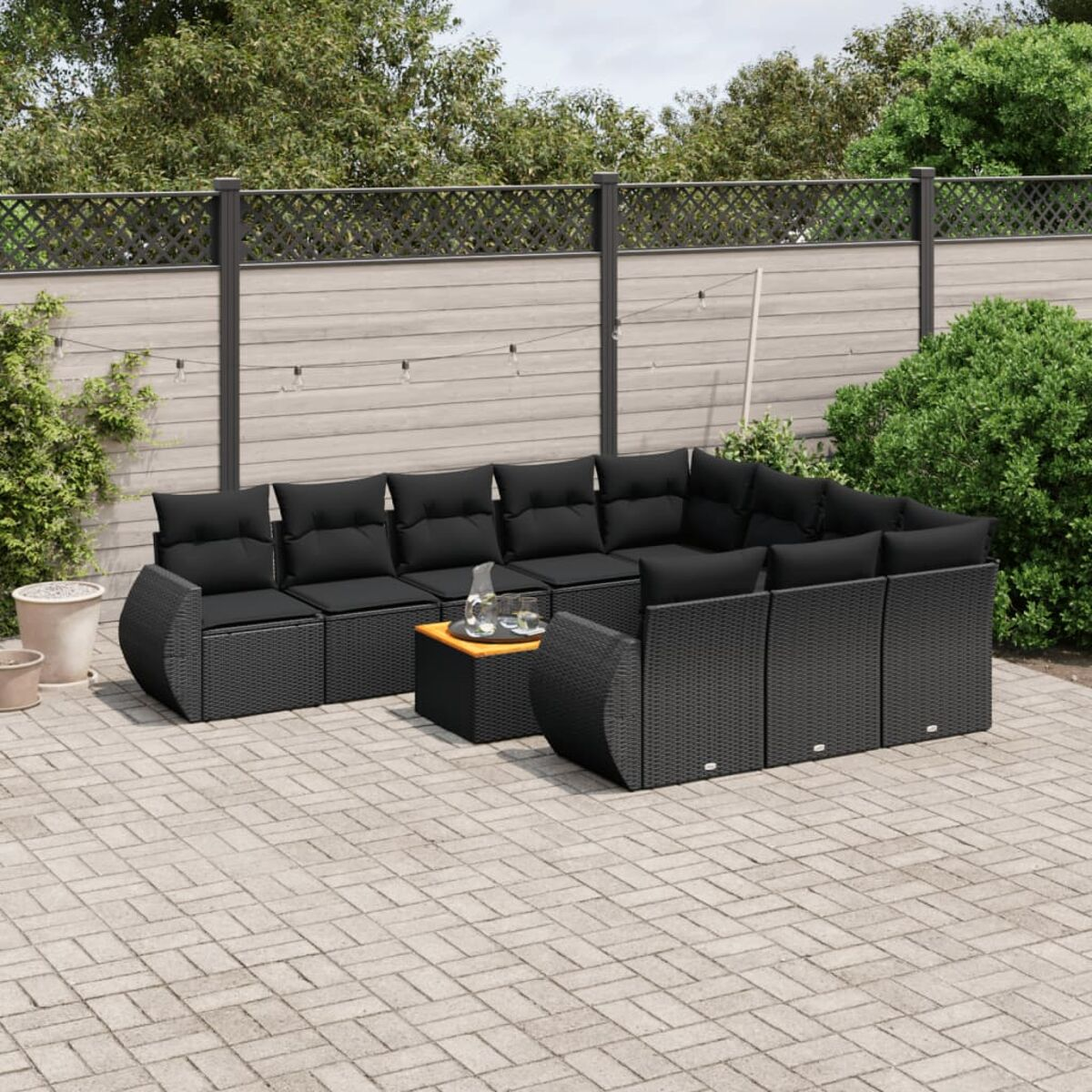 Schwarzes Korbgeflecht-Gartenmöbelset. Schwarze Kissen. Kleiner Holztisch.