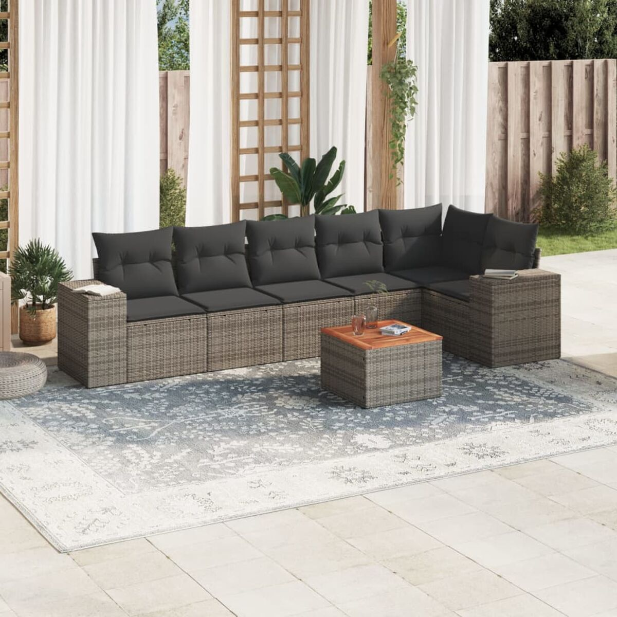 Outdoor-Sitzgruppe mit grauen Korbmöbeln, Kissen und Tisch. Eine Terrasse.