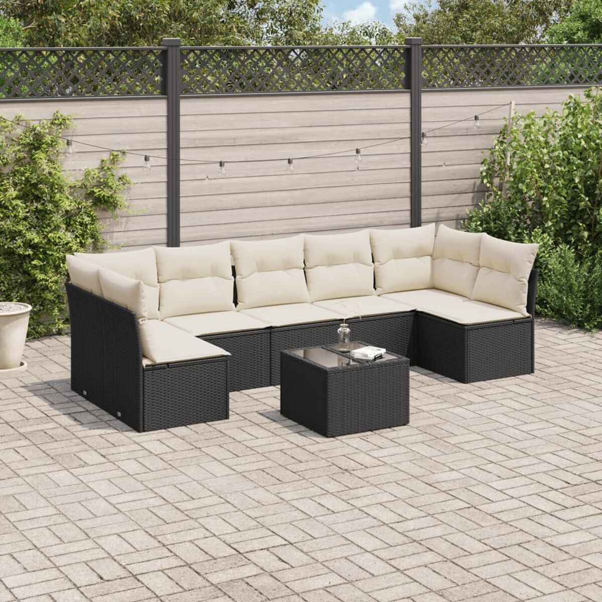 Schwarzes Korbmöbel-Ecksofa mit cremefarbenen Kissen und einem schwarzen quadratischen Tisch.