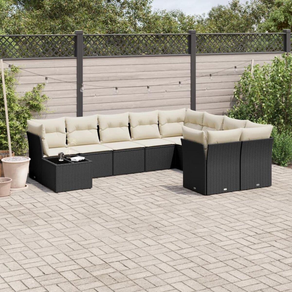 Schwarzes Rattan-Gartenmöbel-Set. Enthält ein Ecksofa und einen Couchtisch auf einer Terrasse.